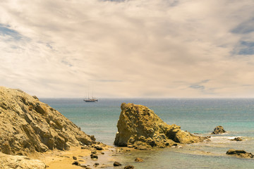Sailboat at Lolantonis beach at Paros island in Greece against a dramatic sky.
