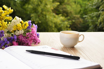 Open notebook with cup of coffee on wooden desk