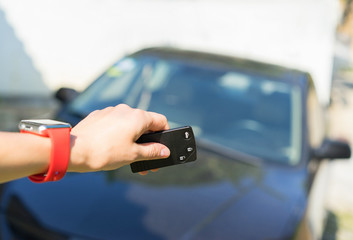 Women's hand with smart watch presses on the remote control car alarm systems