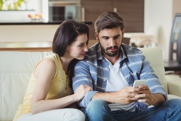 Couple using mobile phone on sofa