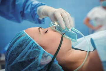 Surgeon adjusting oxygen mask on patient mouth 