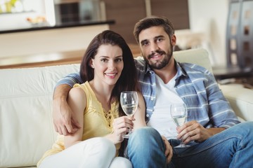 Happy couple relaxing on sofa and holding glasses of champagne