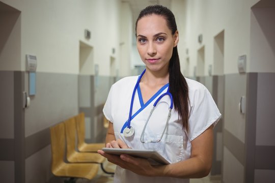 Portrait of female nurse using digital tablet in corridor