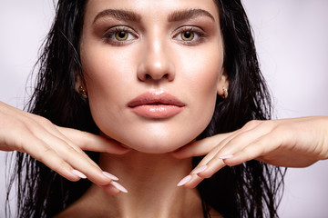 Portrait of a young brunette woman with hining wet make-up and s