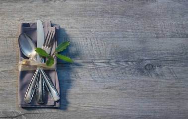 Besteck mit Serviette auf grauem Holz