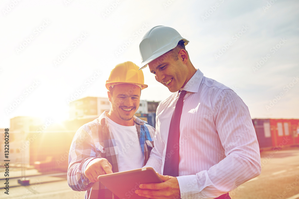 Sticker happy builders in hardhats with tablet pc outdoors