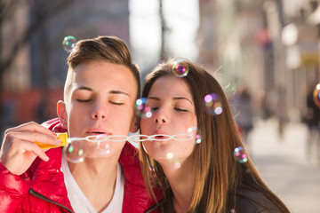 Young couple blowing bubbles in the city