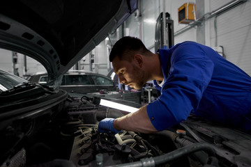 mechanic man with lamp repairing car at workshop