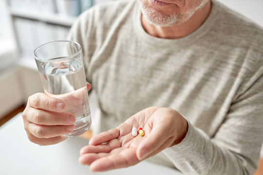 Close Up Of Old Man Hands With Pills And Water