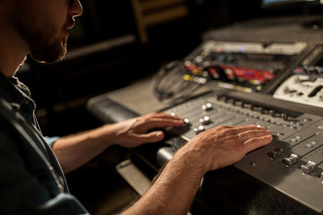 man using mixing console in music recording studio