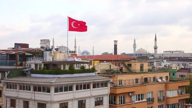 Turkish flag over Istanbul rooftops with mosques on background. Flag waving with strong wind in the city of Istanbul. Pan right movement.