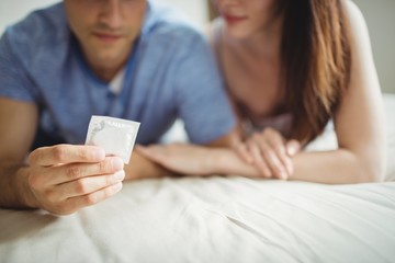 Close-up of couple with a condom on bed - obrazy, fototapety, plakaty