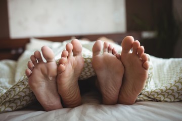 Couple showing their feet while lying on a bed 