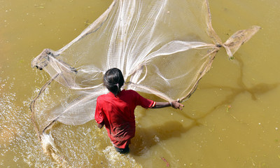Cambodian girl is fishing at the muddy waters