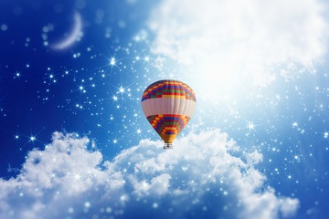 Hot air balloon in blue sky with bright stars and crescent