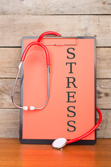 Medical clipboard with text "STRESS" and stethoscope