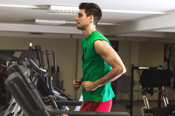 Fototapeta premium Young man running on the treadmill at the gym.