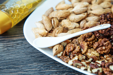 Nuts on a white plate and  honey