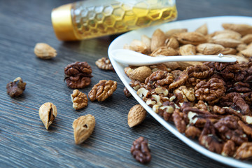 Nuts in a white plate on a wooden background