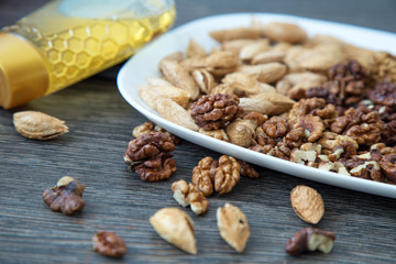 Walnuts and almonds on a wooden surface in white plate