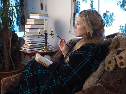 woman with a cat by the window reading a book