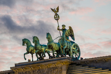 Detail of sculptures on top of Brandenburger Tor in Berlin with pink evening light and soft clouds,...