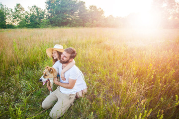 Happy beautiful couple with their Alabai dog in nature with sunset.