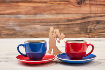 Wooden shape couple and cups. Mugs on saucers. Find a minute for coffee.