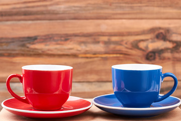 Empty mugs on saucers. Cups on wooden backdrop. Make a break.