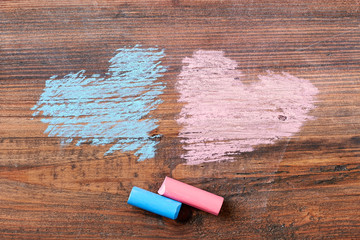 Pink and blue chalk hearts. Chalk sticks on wooden backdrop. Cute art surprise.