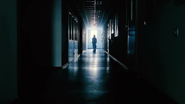 Scientist in protective suit going through dark corridor