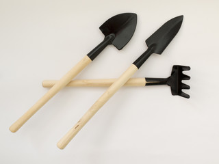 Iron shovel and rake with wooden poles on a white background