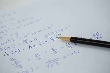 Pen over a sheet of paper with maths formulas