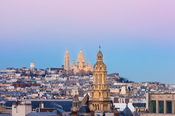 Aerial view of Sacre-Coeur Basilica or Basilica of the Sacred Heart of Jesus at the butte Montmartre and Saint Trinity church at sunset, Paris, France