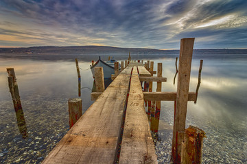 different angle. Exciting long exposure landscape of wooden pier and boat in a lake.Close