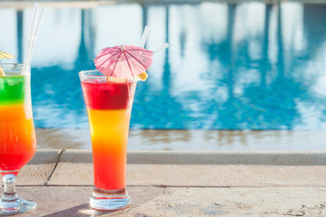 Colored cocktails on a background of water. Colorful cocktails near the pool. Beach party. Summer drinks. Exotic drinks. Glasses of cocktails on table near pool. Summer drinks photo concept. Сocktail