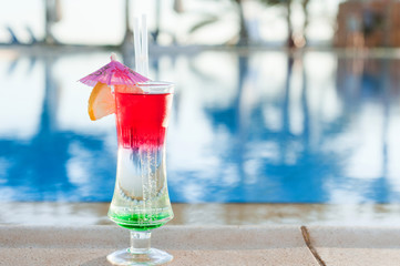 Colored cocktails on a background of water. Colorful cocktails near the pool. Beach party. Summer drinks. Exotic drinks. Glasses of cocktails on table near pool. Summer drinks photo concept. Сocktail