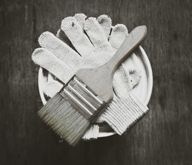 paints, brushes and gloves on a wooden table, hard work concept