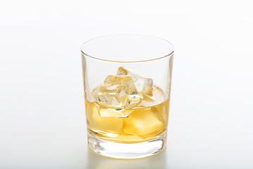 Glass of whiskey and ice on white background