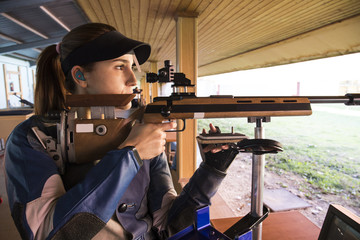 Woman with a sporting rifle aiming in a shooting range