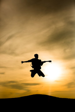 guitarist silhouette jumping with sunset