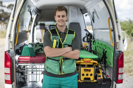 Paramedic standing with arms crossed in front of ambulance