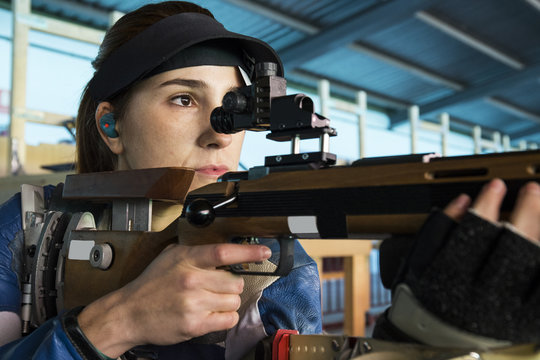 Woman with a sporting rifle aiming in a shooting range