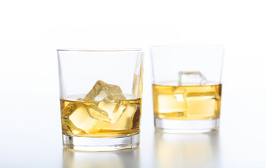 Glasses of whiskey and ice on white background