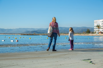 Kvinna och barn tittar ut &ouml;ver en strand med bojar till fisken&auml;t