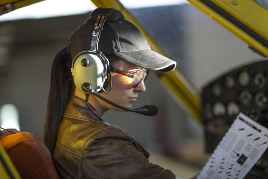 Female pilot inspecting light aircraft cockpit