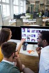 Graphic designers discussing over computer at their desk