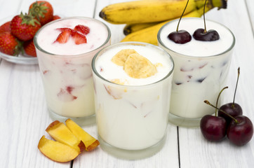 Strawberry, banana and cherry yogurt on a white wooden background. Healthy diet