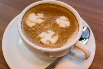 A cup of Latte art on wooden bar