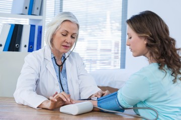 Female doctor checking blood pressure of a patient